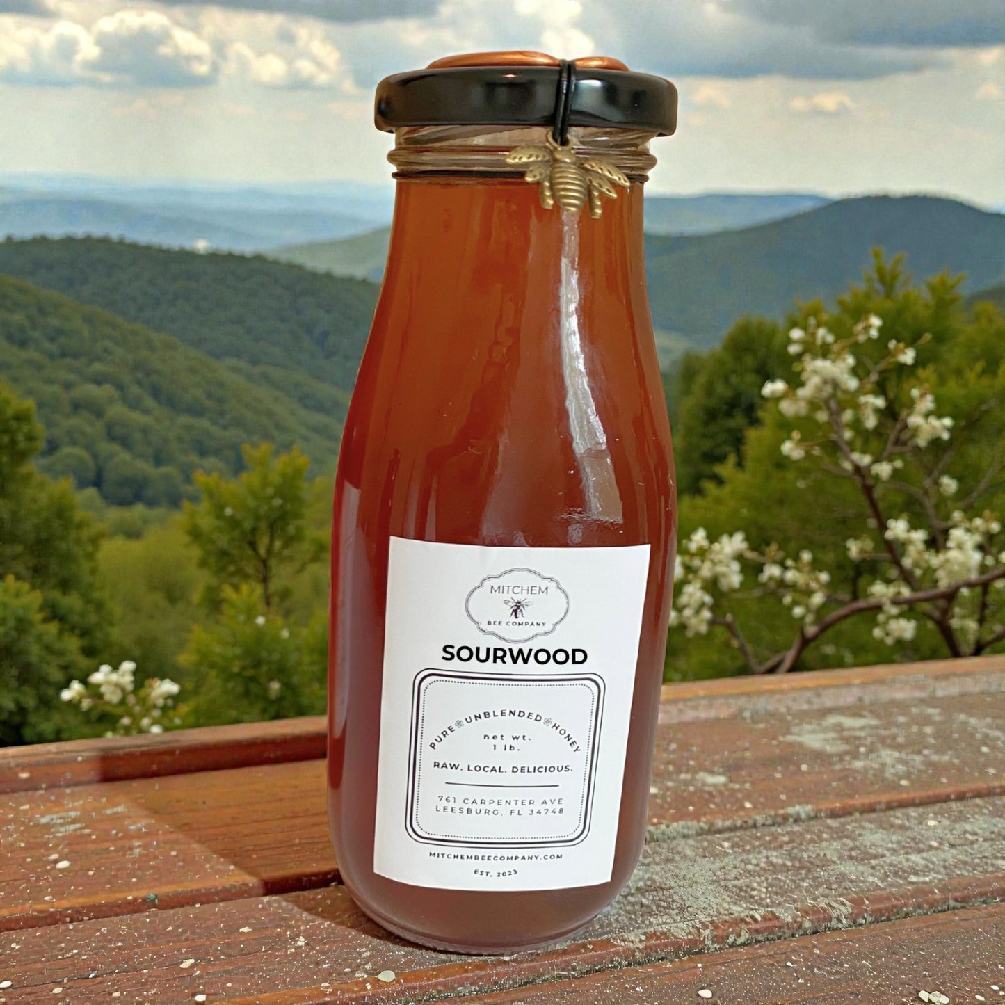 Bottle of Sourwood honey with a scenic background of mountains and trees.
