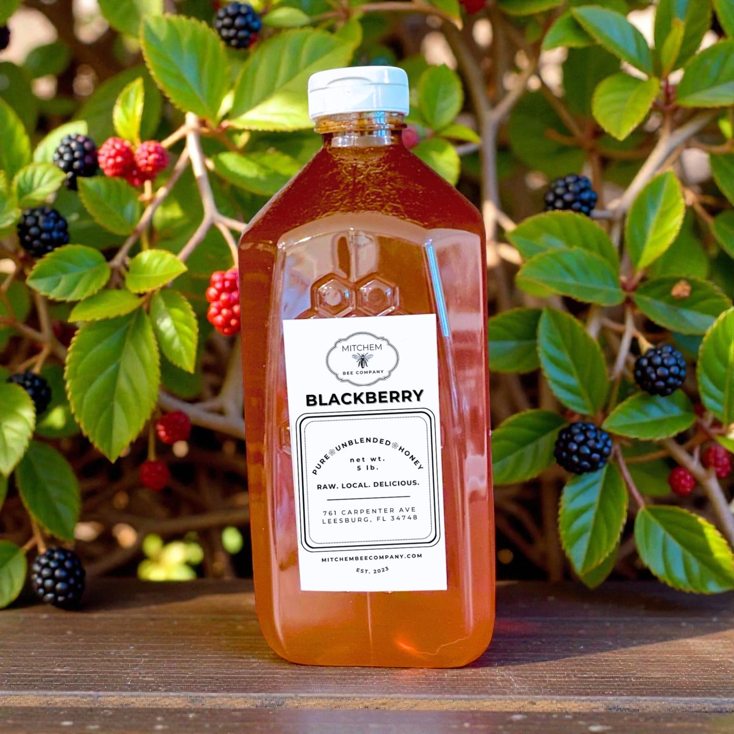 Bottle of blackberry honey with a natural background of green leaves and berries