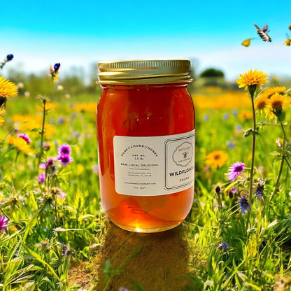 Jar of Mitchem Bee Company chunk wildflower honey with a label in a field of wildflowers