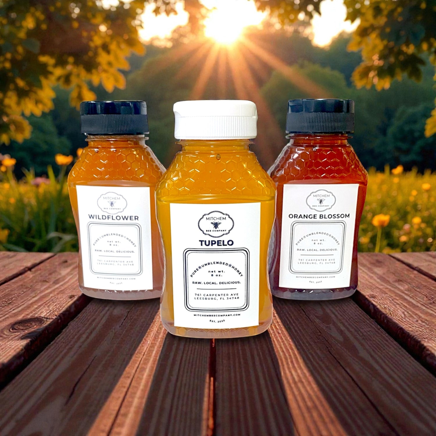 Three honey bottles with labels on a wooden surface outdoors during sunset.